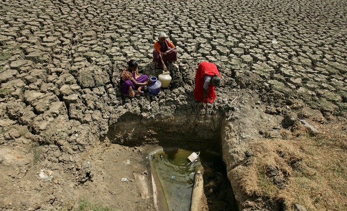 Women fetch water from an opening made by residents at a dried-up lake in Chennai, India.