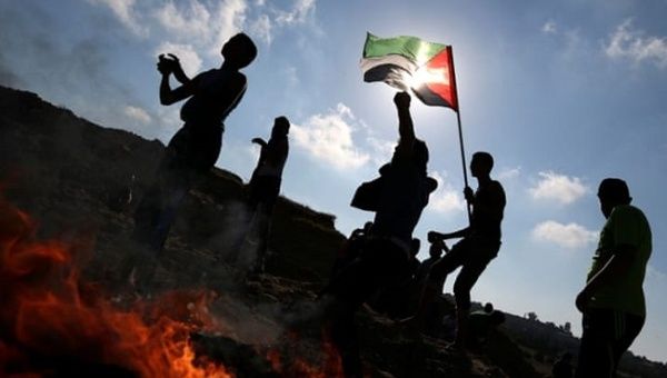 Palestinian protesters hurl stones towards Israeli troops during clashes near Gaza border