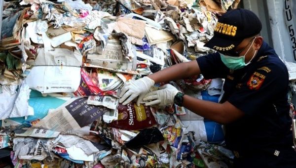 A customs officer shows a container of waste paper imported from Australia. Surabaya, East Java province. July 9, 2019