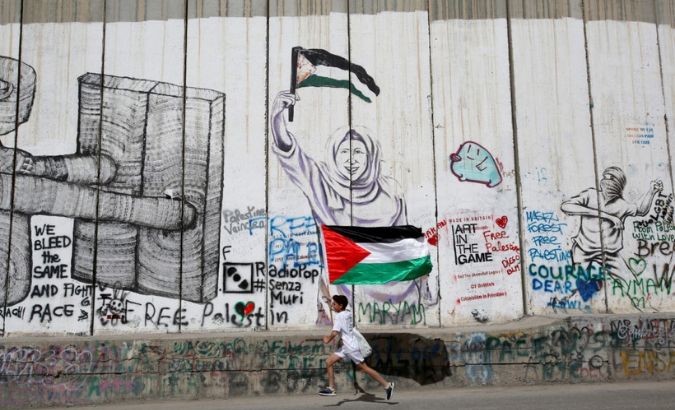 A Participant runs past the Israeli barrier during the annual Palestine Marathon in Bethlehem, in the occupied West Bank, March 23, 2018.