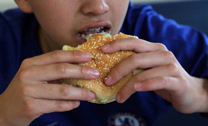Boy eats a hamburger at a fast-food restaurant in Lima, Peru.