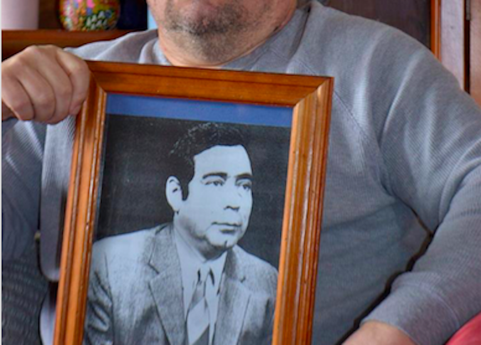Donato holding the portrait of his deceased father in his home