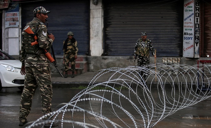 Indian security forces personnel stand guard next to concertina wire laid across a road during restrictions after the government scrapped special status for Kashmir.