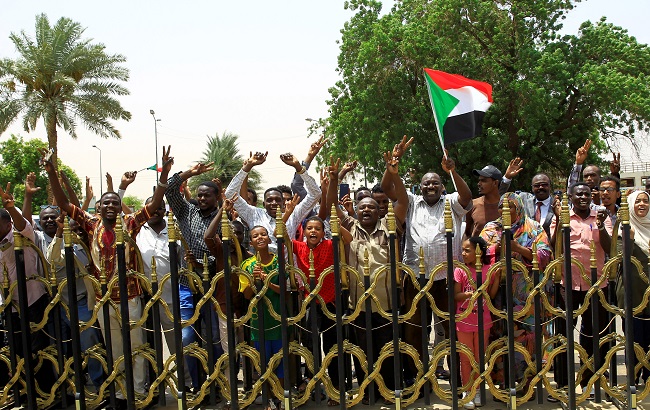 Sudanese people carry their national flag and chant slogans as they celebrate the signing of a constitutional declaration between Deputy Head of Sudanese Transitional Military Council, Mohamed Hamdan Dagalo and Sudan's opposition alliance coalition's leader Ahmad al-Rabiah, outside the Friendship Hall, in Khartoum, Sudan August 4, 2019.