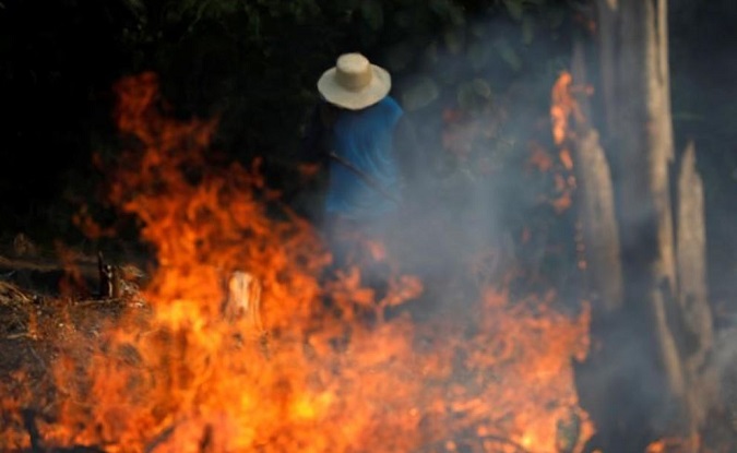 A man works in a burning tract of Amazon jungle as it is being cleared by loggers and farmers in Iranduba, Amazonas state, Brazil August 20, 2019.