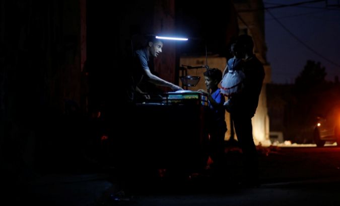 A Palestinian man sells falafel as he uses a battery-powered light during power cut in the northern Gaza Strip August 26, 2019.