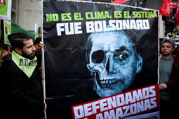 Demonstrators hold a placard with a skull and the face of Brazilian President Jair Bolsonaro that reads 