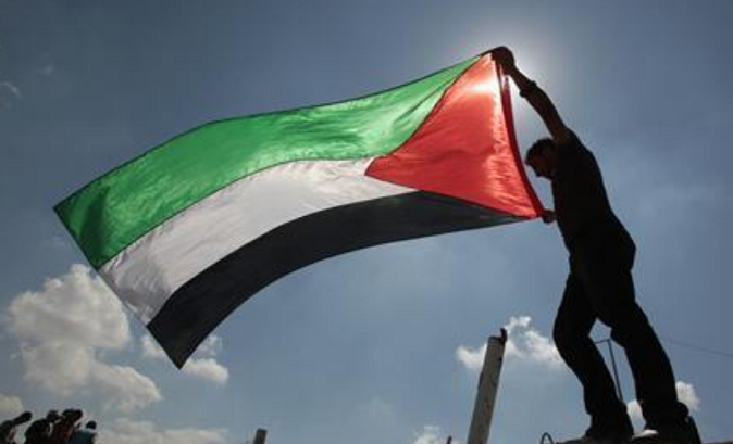 A Palestinian holds a flag during a protest near the Erez border crossing between Israel and northern Gaza Strip October 5, 2011