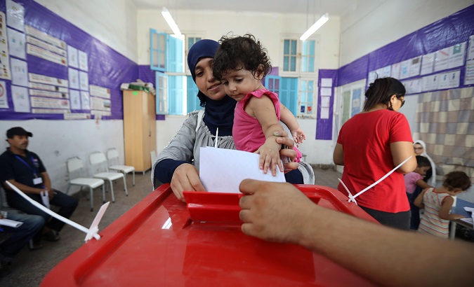 A woman carries a child as she casts her vote at a polling station during presidential election in Tunis, Tunisia September 15, 2019.