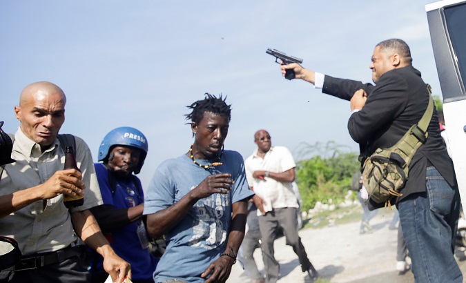 People run as Haiti's Senator Jean Marie Ralph Fethiere holds a gun in Port-au-Prince, Haiti September 23, 2019.