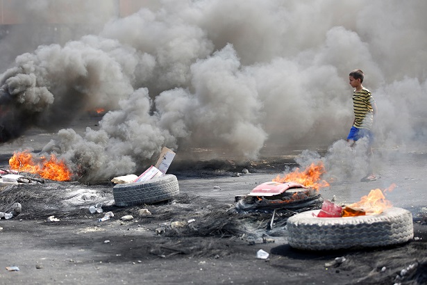 A boy is seen near burning tires during a curfew, two days after the nationwide anti-government protests turned violent, in Baghdad, Iraq October 3, 2019.