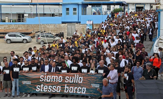 Students and shipwreck survivors carry a banner reading 'We are in the same boat' in Sicily, Italy, Oct. 3, 2019.