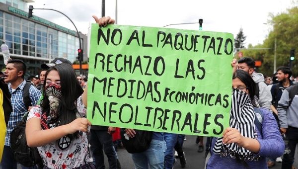 People hold a placard reading 'No to the pack of measures. Rejection of neo-liberal economic measures' in Quito, Ecuador, Oct. 4, 2019.