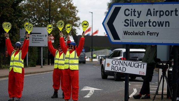 Extinction Rebellion protesters dressed as airport marshalls block the road during a demonstration, near London City Airport, in London, Britain, October 10, 2019. 