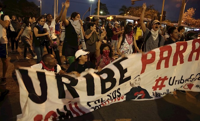 Students hold banner referring to ex President Uribe as leader of paramilitary right-wing forces in Cali, Colombia, Oct. 10, 2019.