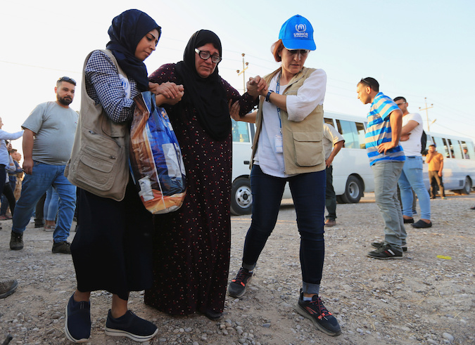 U.N. workers help a Syrian displaced woman, who fled violence after the Turkish offensive against Syria, upon arrival at a refugee camp in Bardarash on the outskirts of Dohuk, Iraq October 16, 2019.