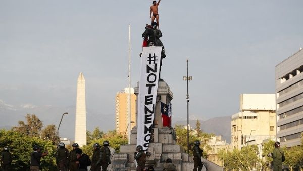 A demonstrator stands atop the monument on which a banner reading 'We have no fear' hangs at Plaza Baquedano in Santiago, Chile Oct. 22, 2019.