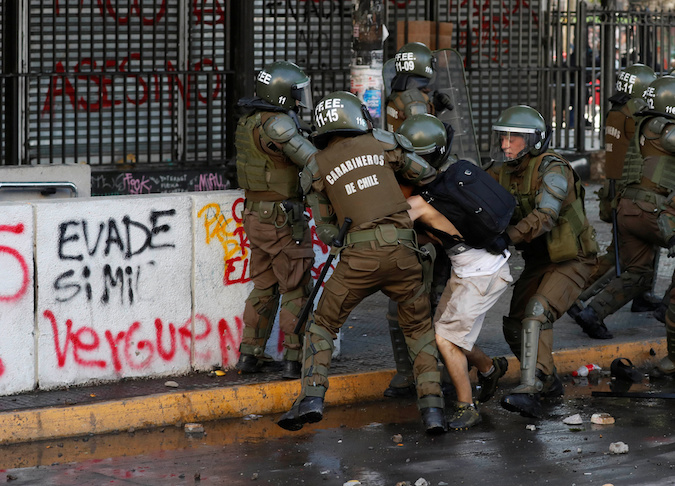 Riot police detain a demonstrator during a protest against Chile's state economic model in Santiago, Chile October 24, 2019.