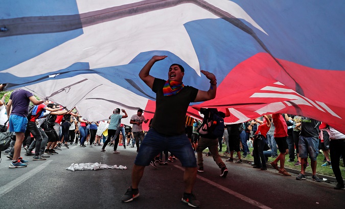Demonstrators carry a giant Chilean national flag during a protest against neoliberal economic model in Santiago, Chile Oct. 25, 2019.