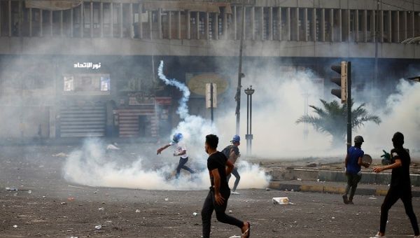 A demonstrator throws away a tear gas canister during the ongoing anti-government protests in Baghdad, Iraq Nov. 11, 2019.