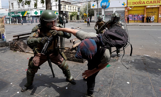 Police officers attack a citizen during a protest against President Sebastian Piñera in Valparaiso, Chile Nov. 12, 2019.