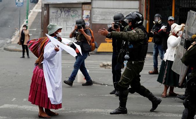 Indigenous woman holds white flags as she faces police officers during a protest in La Paz, Bolivia Nov. 13, 2019.