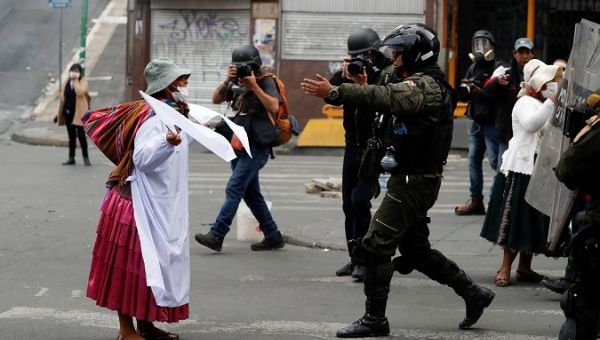 Indigenous woman holds white flags as she faces police officers during a protest in La Paz, Bolivia Nov. 13, 2019.