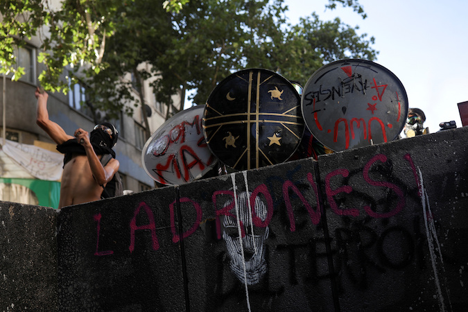 Demonstrators take cover with makeshift shields during a protest against Chile's government, in Santiago, Chile November 20, 2019.