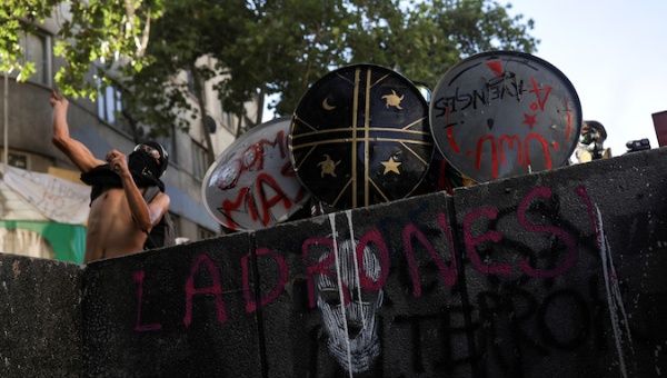 Demonstrators take cover with makeshift shields during a protest against Chile's government, in Santiago, Chile November 20, 2019.