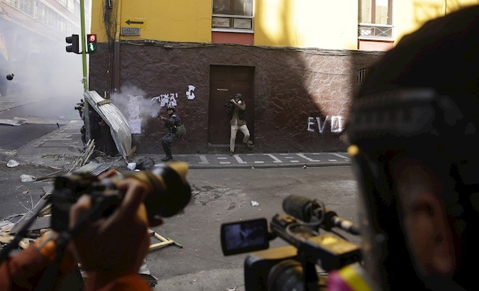 Graphic reporters transmit images of a policeman who shoots tear gas at Evo Morales' supporters in La Paz, Bolivia, Nov. 15, 2019.