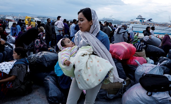 Woman holds her baby as refugees arrive on a ferry from the Lesbos island at the Piraeus port, Greece, Oct. 7, 2019.