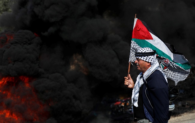 A demonstrator holds a Palestinian flag during a protest against Jewish settlements in Kofr Qadom, in the Israeli-occupied West Bank November 22, 2019.