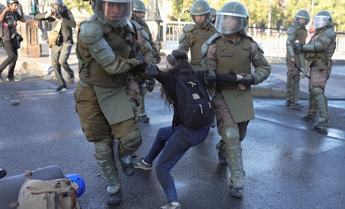 Young woman is detained after being beaten by riot policemen during a protest in Santiago, Chile, Nov. 30, 2019.