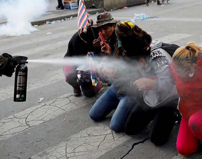 Demonstrators are pepper sprayed by a member of the security forces during clashes between supporters of former Bolivian President Evo Morales and the security forces, in La Paz, Bolivia November 15, 2019.