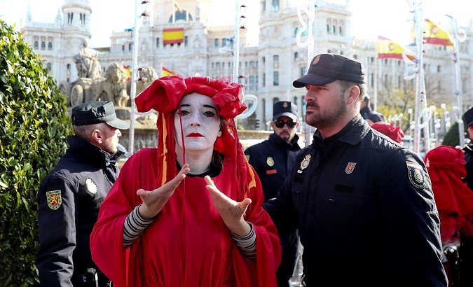 Extinction Rebellion activist is escorted by police officers after staging a protest at Cibeles Fountain in Madrid, Spain, Dec. 3, 2019.