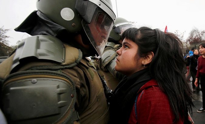 A demonstrator looks at a riot policeman during a protest in Santiago, Chile, Sep. 11, 2016.