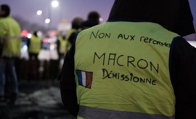 Workers gathering for protest at dawn on Saturday. The yellow vest's sign says, “No to reforms. Step out Macron.” France, Dec. 7, 2019.
