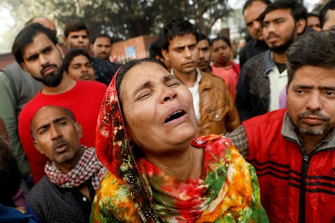 A relative of a victim of a fire that swept through a factory where laborers were sleeping, cries outside a hospital mortuary in New Delhi.