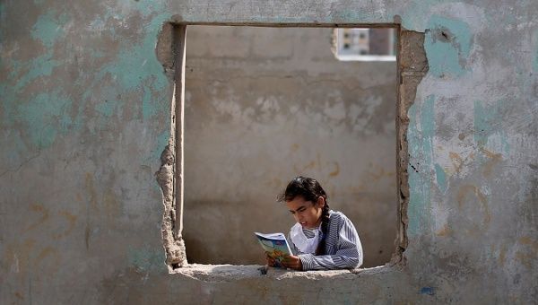 A Palestinian UNRWA schoolgirl holds her book as she stands by a window outside her family home in Al-Shati refugee camp in Gaza City, Oct. 23, 2019.