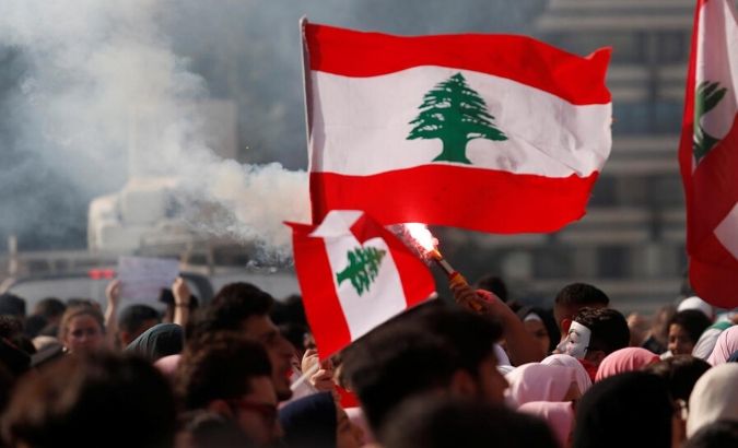 University students light a torch and wave Lebanese flags during anti-government protest in Beirut, Lebanon, Nov. 6, 2019.