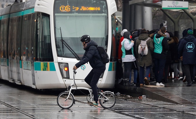 A man riding a bicycle passes near a tramway as the transport workers' strike continues in Paris, France, Dec. 16, 2019.