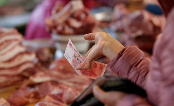 A customer buys pork from a vendor at a market in Beijing, China.