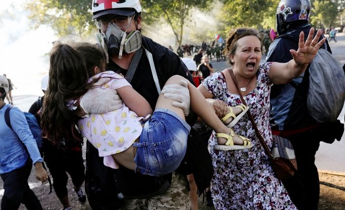 A woman gestures next to a medical volunteer carrying a child during a protest against Chile's government in Santiago, Chile December 20, 2019.