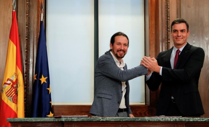 Spain's acting Prime Minister Pedro Sanchez and Unidas Podemos leader Pablo Iglesias shake hands as they present their coalition agreement at Spain's Parliament in Madrid, Spain, Dec.30, 2019.