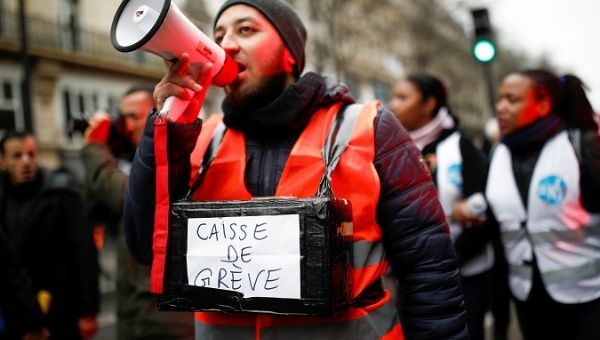 A protestor holds a box for strike fund donations in Paris, France, Dec. 28, 2019.