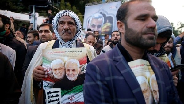 A man holds a picture of Iranian Major-General Qassem Soleimani, head of the elite Quds Force, and Iraqi militia commander Abu Mahdi al-Muhandis, who were killed in an air strike at Baghdad airport, during their funeral procession in Ahvaz, Iran January 5, 2020.