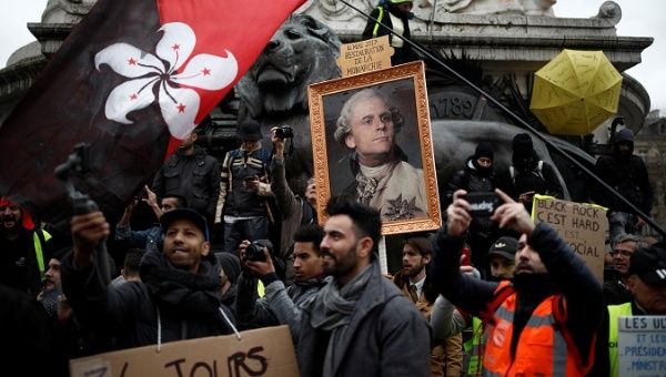 Citizens hold a placard with a portrait of Macron as King Louis XVI at a demonstration in France, January 9, 2020.