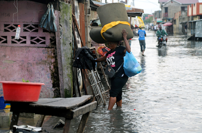 A Congolese woman carries her belongings as she wades through floodwaters along a street after the Congo River burst its banks due to heavy rainfall in Kinshasa, Democratic Republic of Congo January 9, 2020.