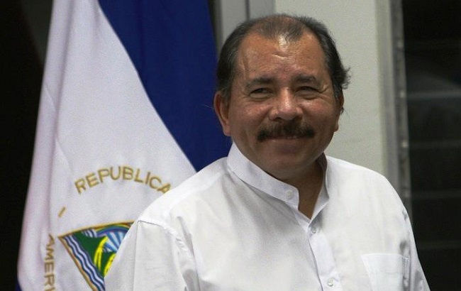Nicaraguan President Daniel Ortega poses for picture in front of his country's flag
