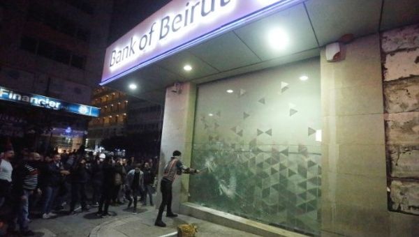 Protesters smash the window of a Bank of Beirut office as demonstrations against the government continue in Beirut, Lebanon January 14, 2020. 